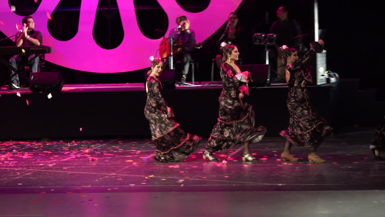 At 0:01 in Cabo San Lucas, Mexico, the dancers move farther across the foreground as the seated keyboard player and string musician remain visible on the raised stage platform.