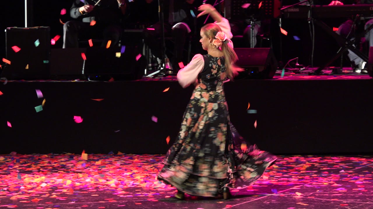 Female stage performer in a floral dress with confetti falling.