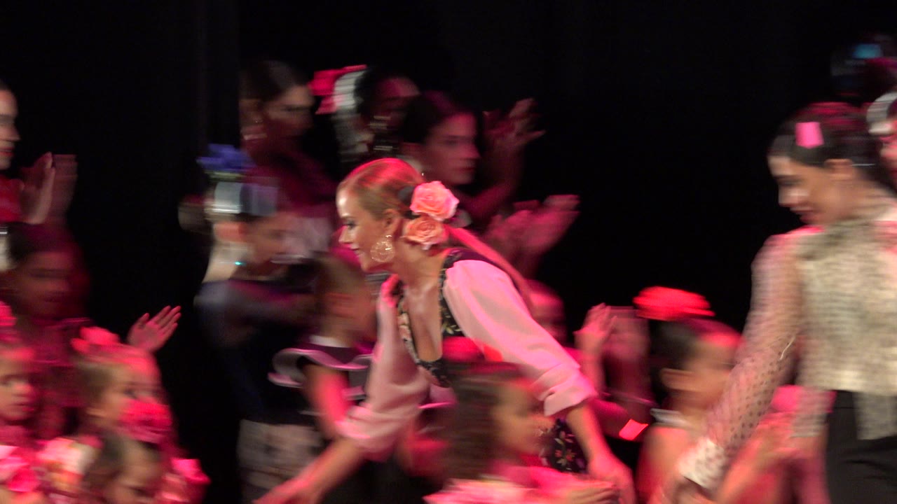 Children and adults on a dark stage under red lighting.