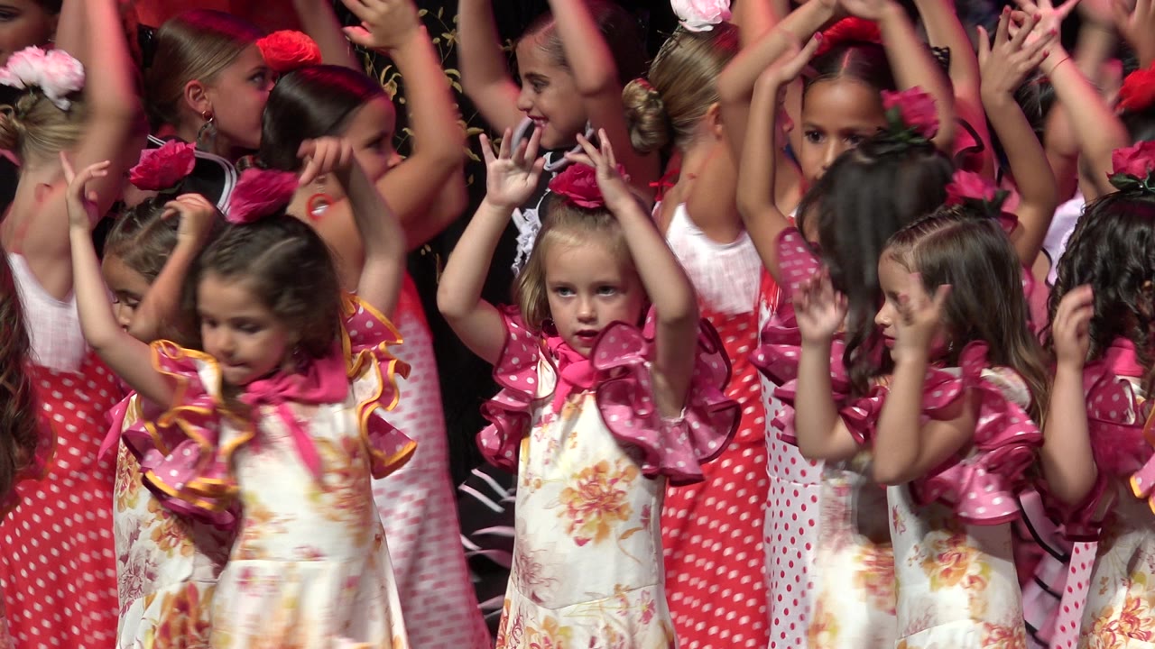At 0:01 in Cabo San Lucas, the children remain tightly grouped as several girls face forward and others turn sideways with arms still raised.