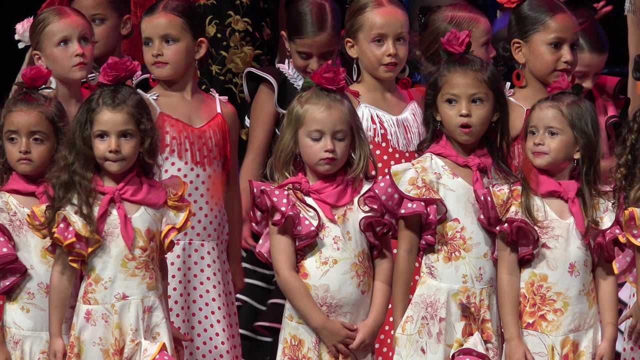 Children in colorful costumes standing together on a stage.
