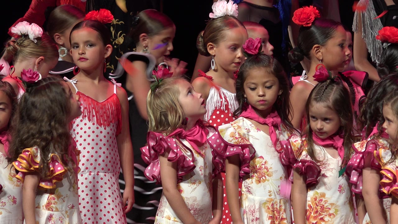 Costumed girls standing close under strong stage lighting.