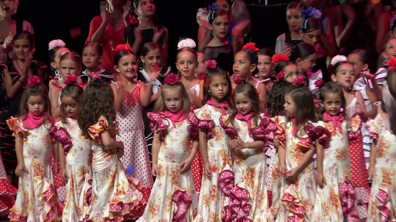 Front row children clap with more performers behind them.