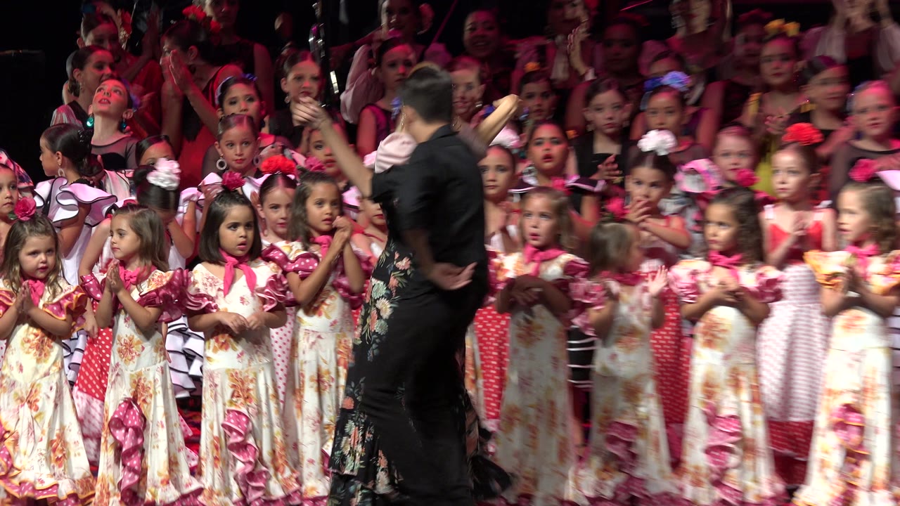 Couple dancing in front of children clapping on stage.