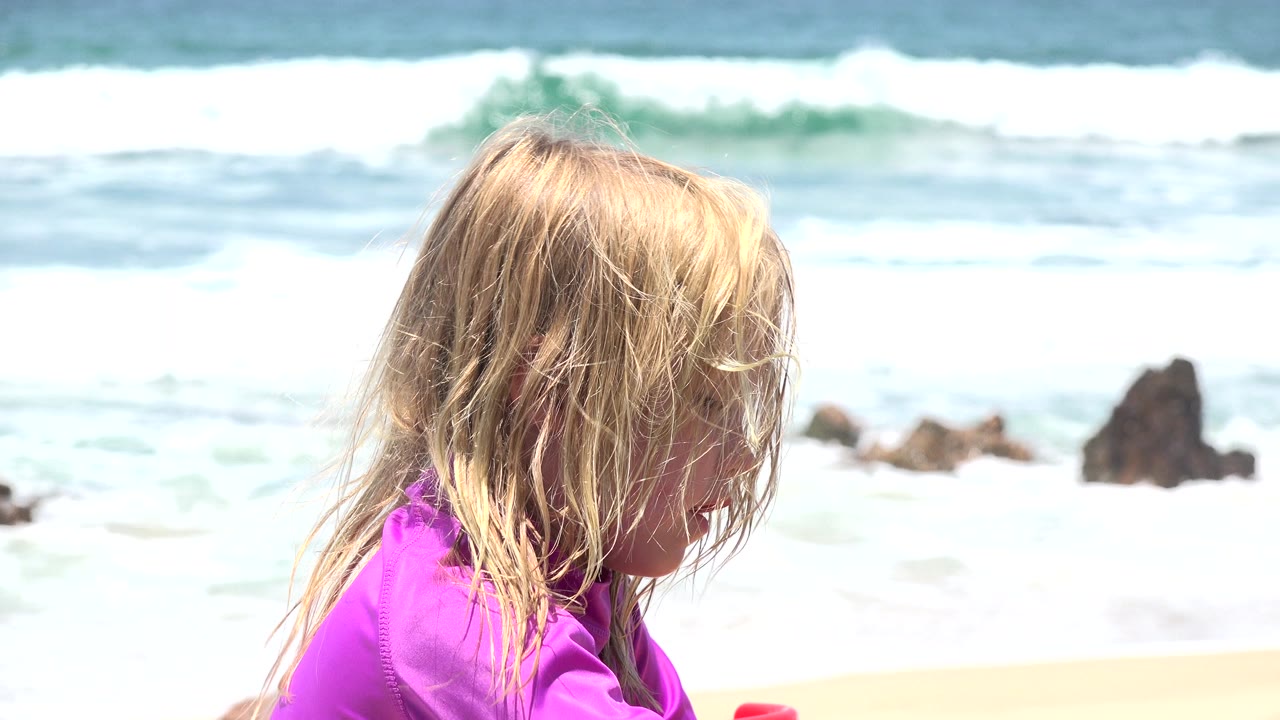 Blonde child in profile with waves behind