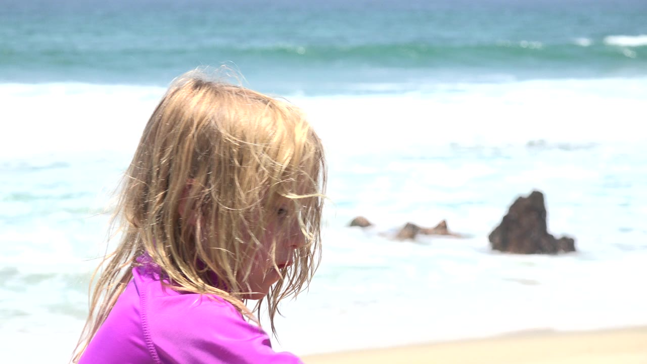 Child sits in foreground with face partly hidden by hair.