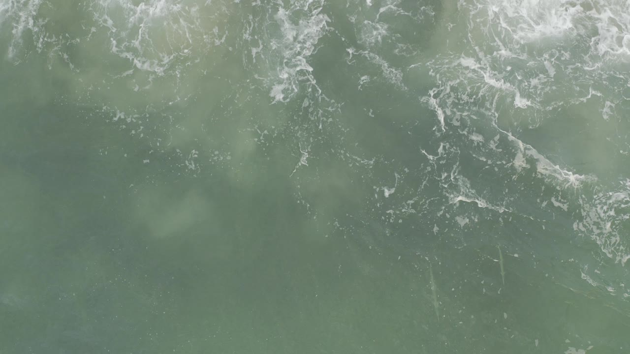 Overhead blue-green ocean water in Baja California Sur, Mexico, with white foam breaking across the upper edge and no visible people.