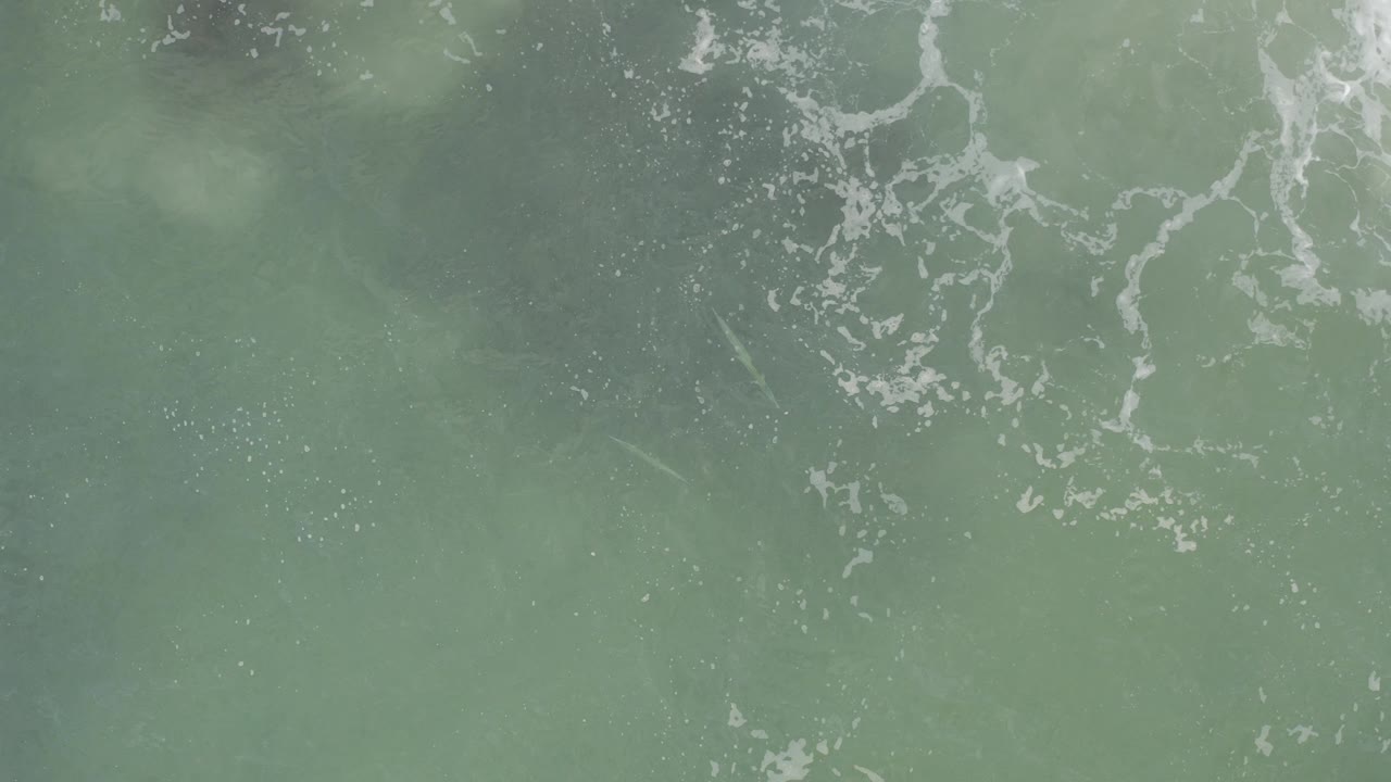 Overhead view of green ocean water in Baja California Sur, Mexico, with thin white foam patterns near the top and no visible people.