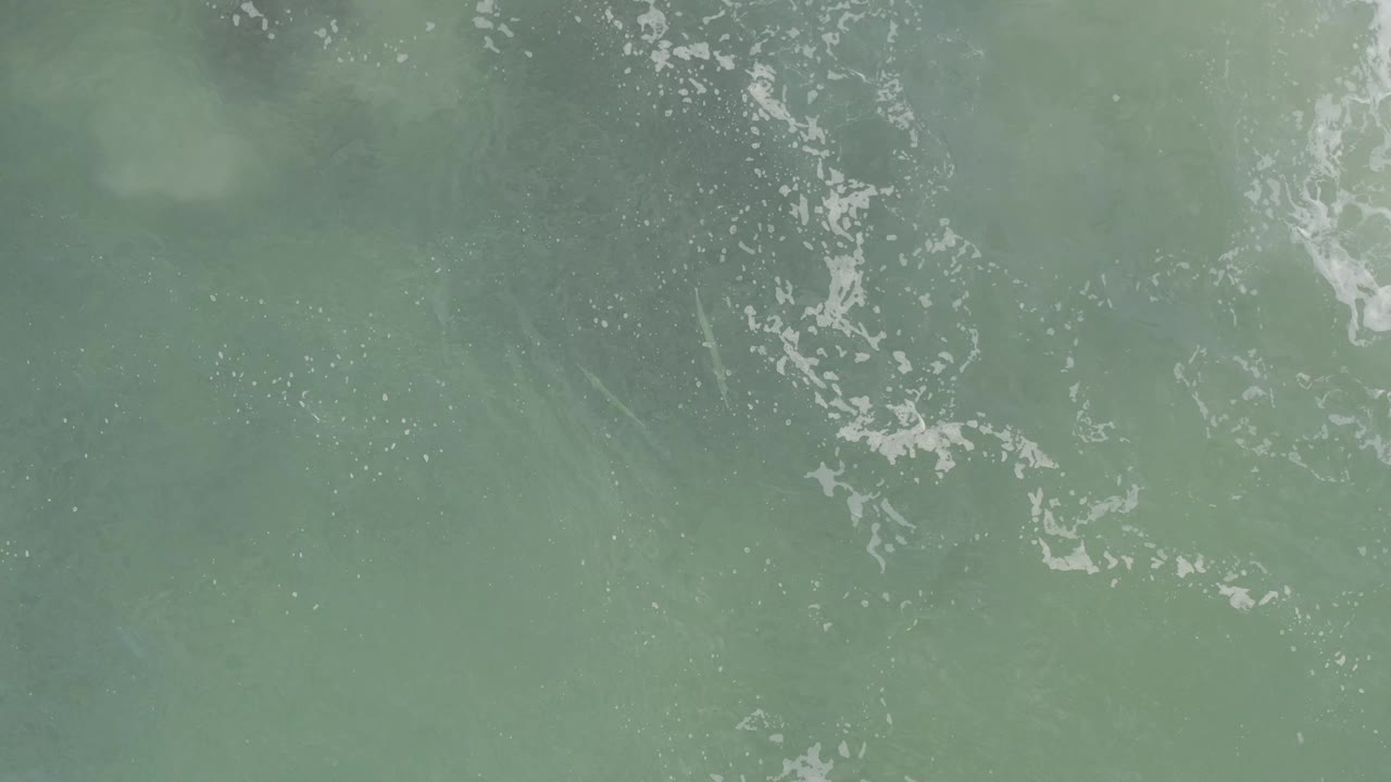 Aerial-looking frame of Baja California Sur ocean water with foamy white ripples crossing the upper half and no visible people.