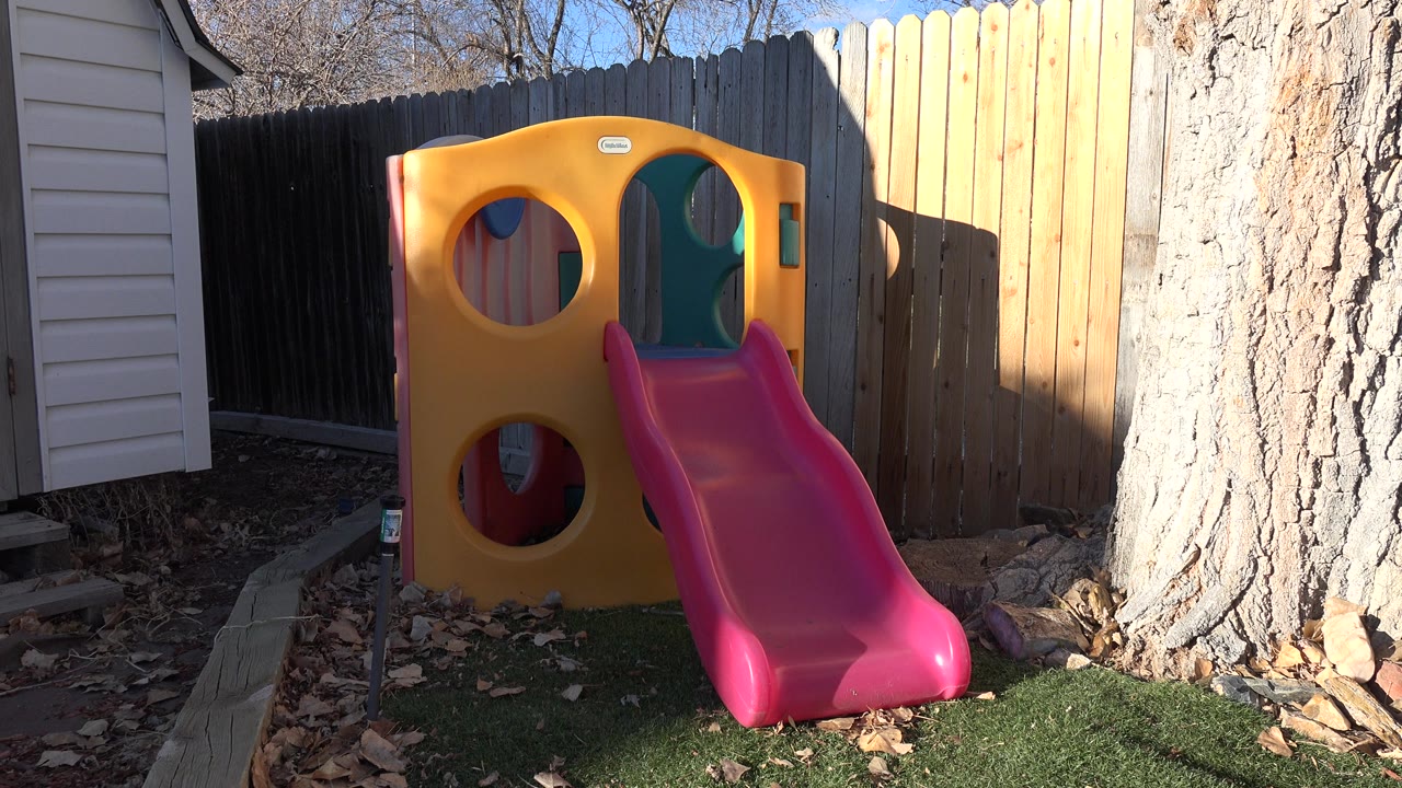 Empty backyard plastic slide and playset in sun