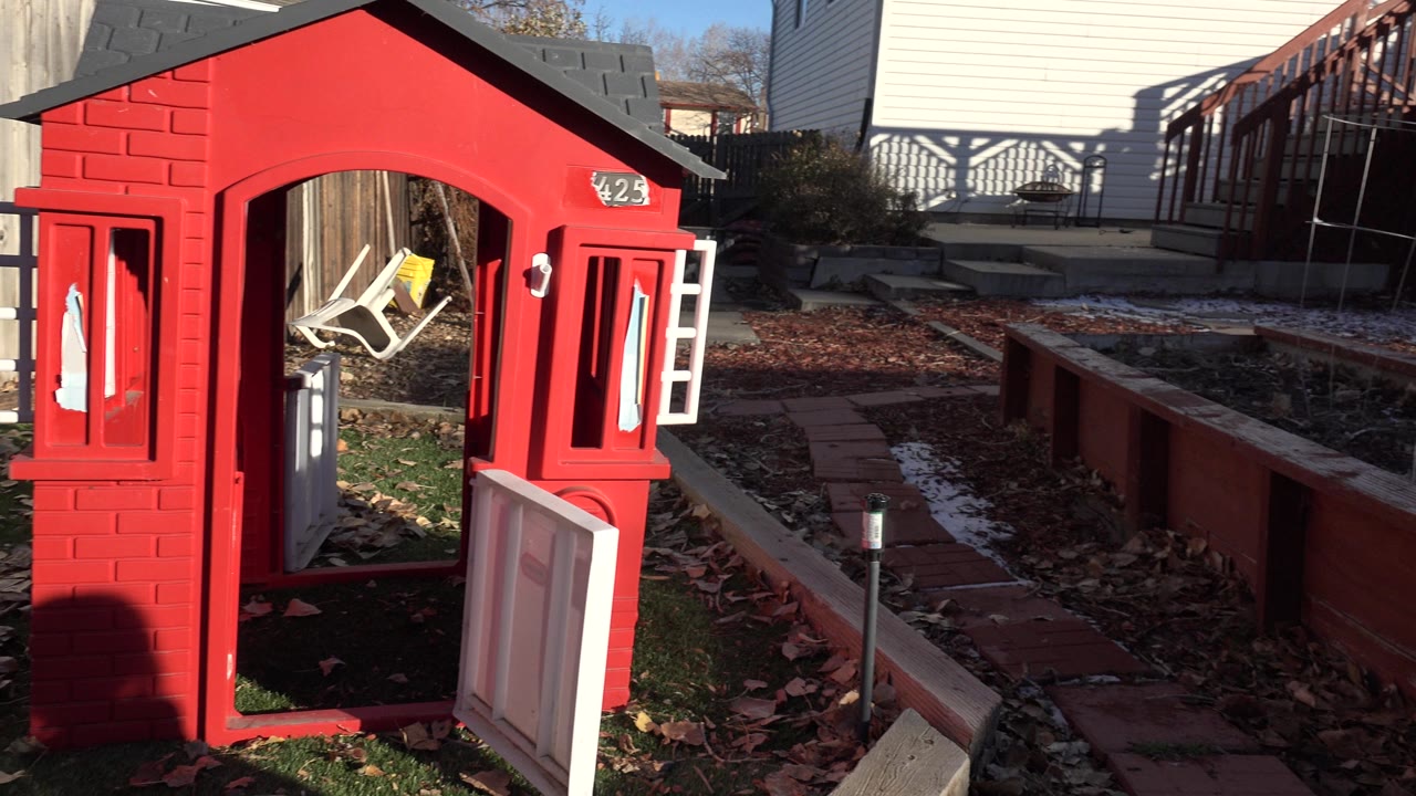Red playhouse beside raised backyard garden beds.