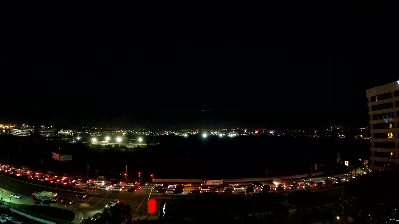 Night traffic on a curving road with distant city lights