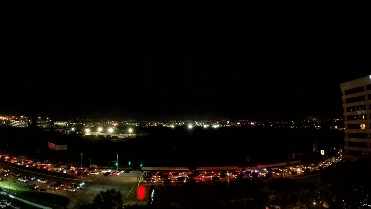Night traffic and distant city lights beside a white high-rise