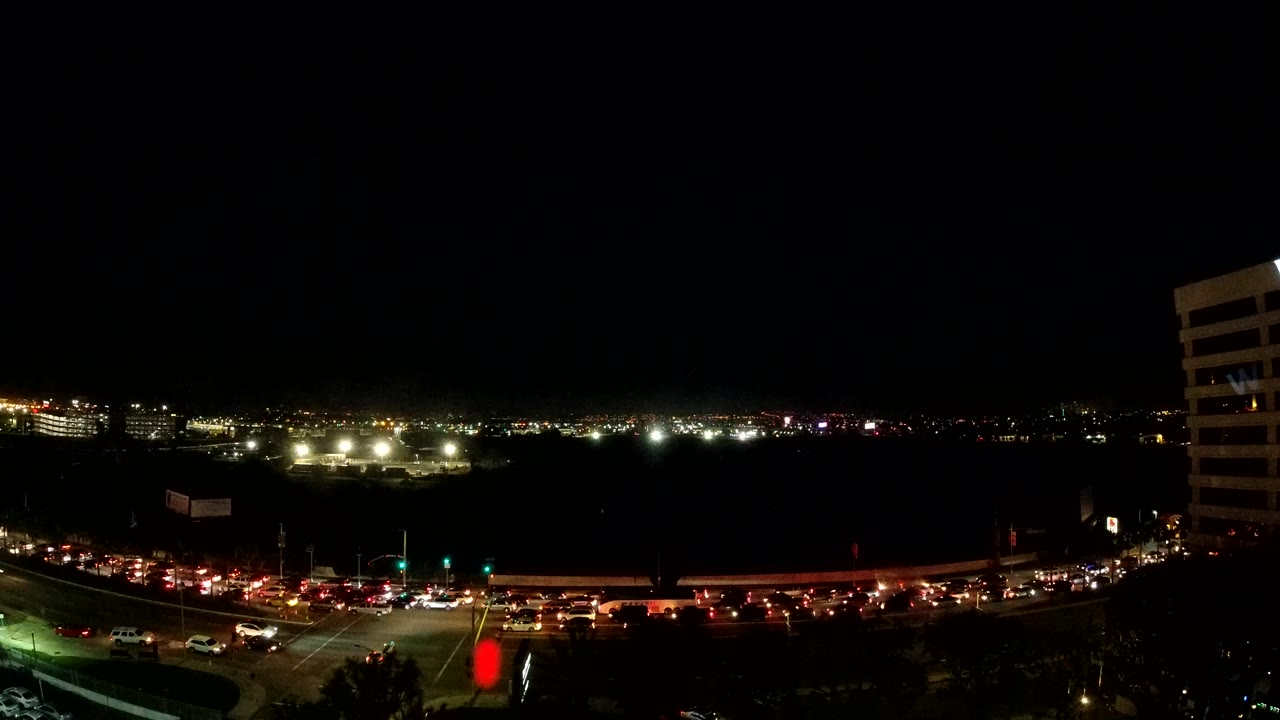 A second Los Angeles night frame shows traffic compressed along the lower road, red taillight trails, bright white lights in the distance, and no visible people.