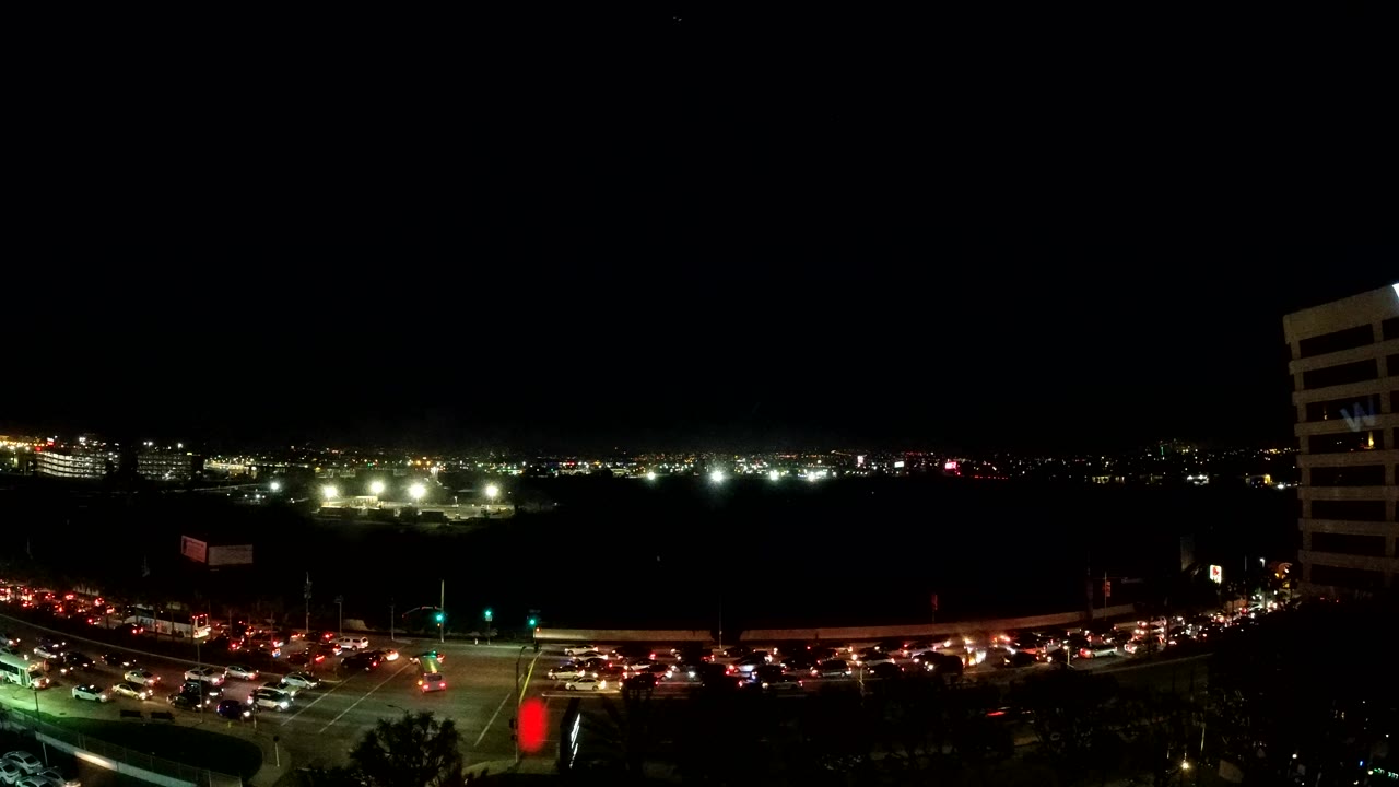 Cars queued at a nighttime intersection with city lights beyond.
