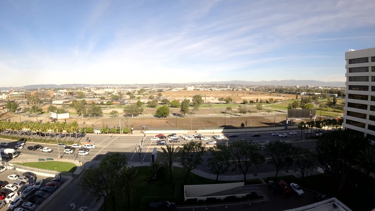 Third frame presents Los Angeles traffic under bright sky, with the right-side office tower, parked cars at the lower left, and no visible people.