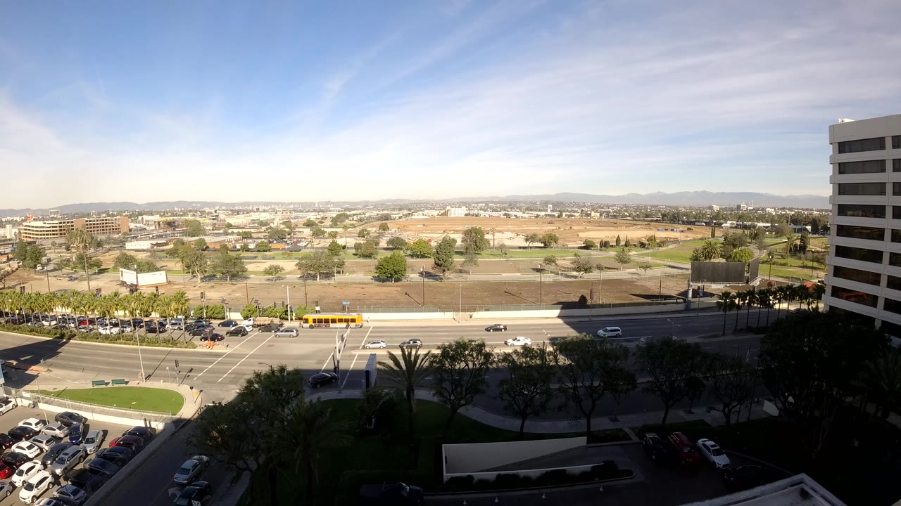 Wide elevated view of traffic crossing a bright urban intersection.