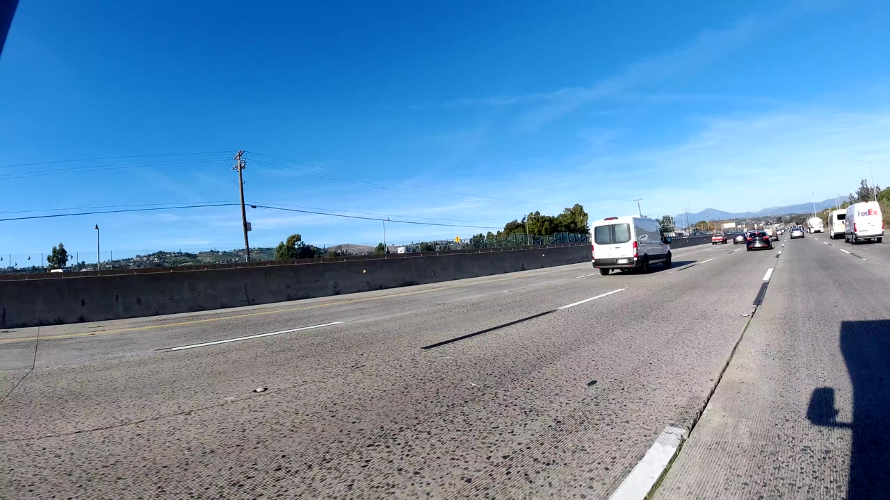 Freeway lanes with a white van ahead and traffic in the distance.
