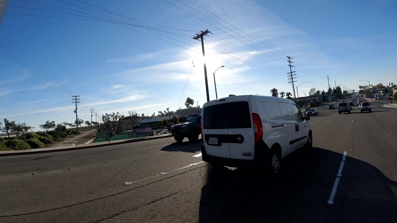 Traffic scene in Orange, California with a white van close to the camera, other cars in nearby lanes, strong sun, and no visible people.