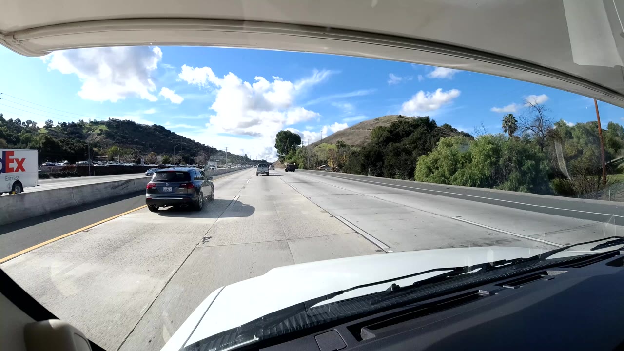 Vehicle windshield view of freeway traffic with a FedEx truck on the right.