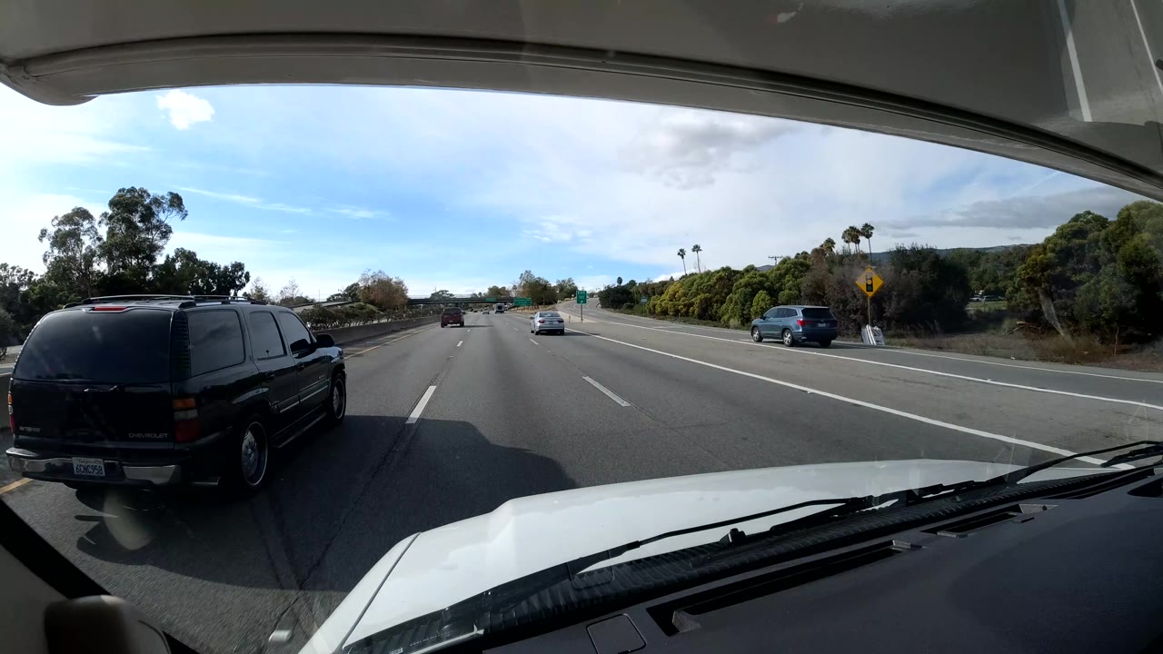 Black SUV beside the vehicle on a highway under bright daytime sky.