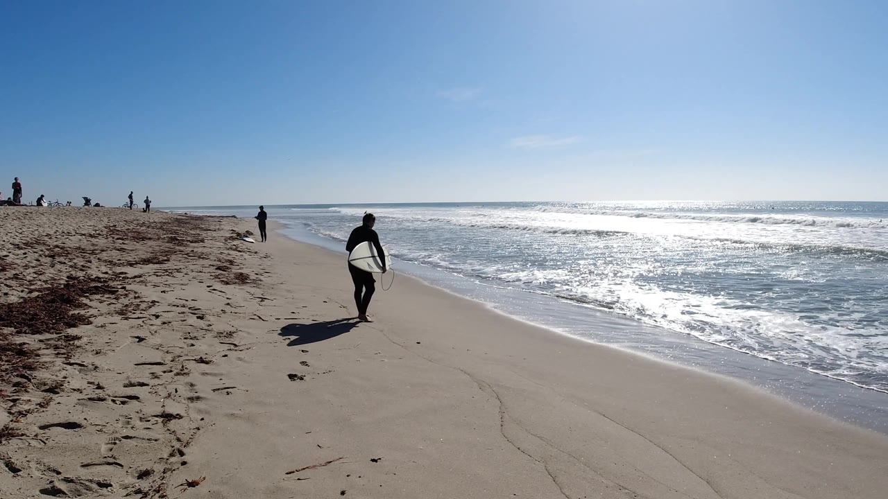 At Trestles Beach, California, the surfer angles closer to the surf with the board visible against the sand, while whitewater spreads across the right side of the frame.