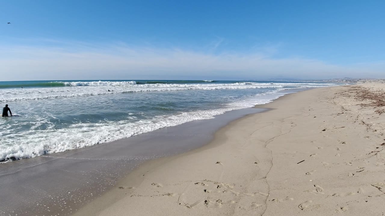 Bather at the edge of the surf with waves rolling in.