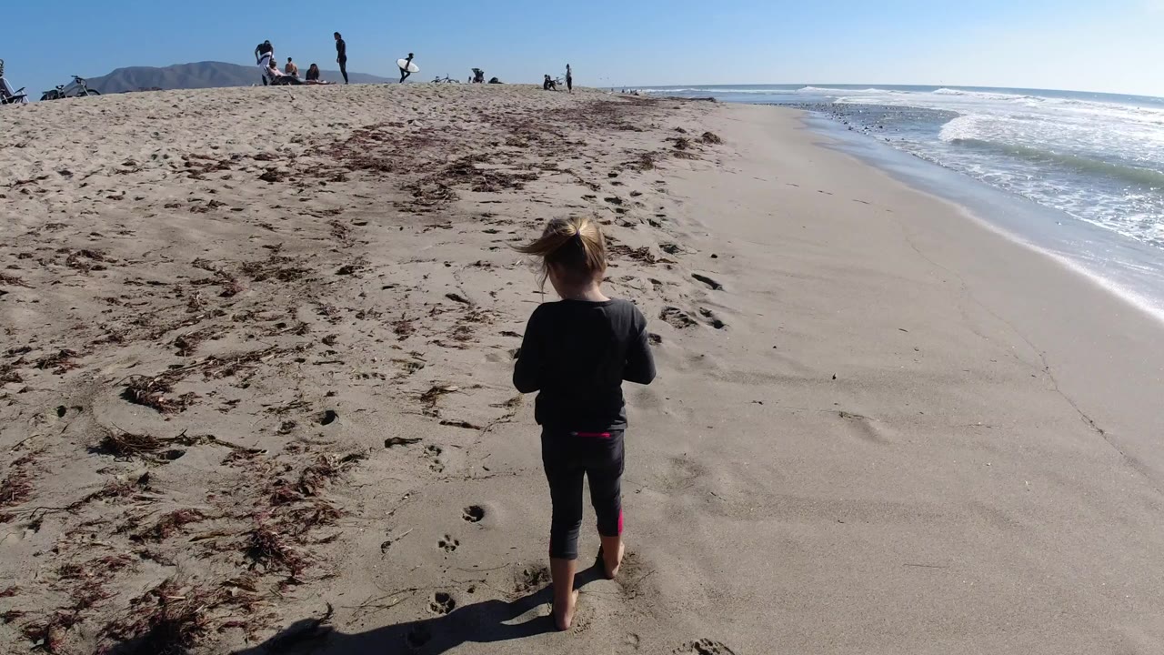 Child continues walking along the beach near the waterline.