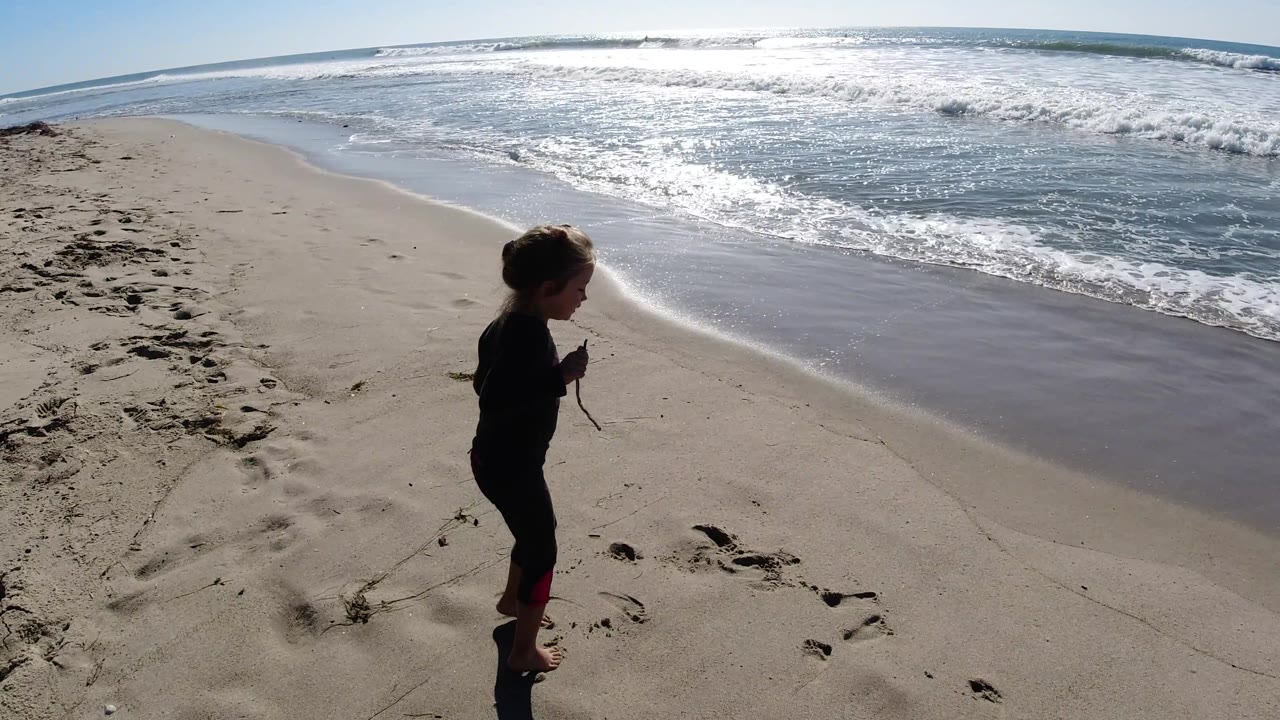 At Trestles Beach, California, the child appears in profile near the right side of the frame as waves break across the bright ocean background.
