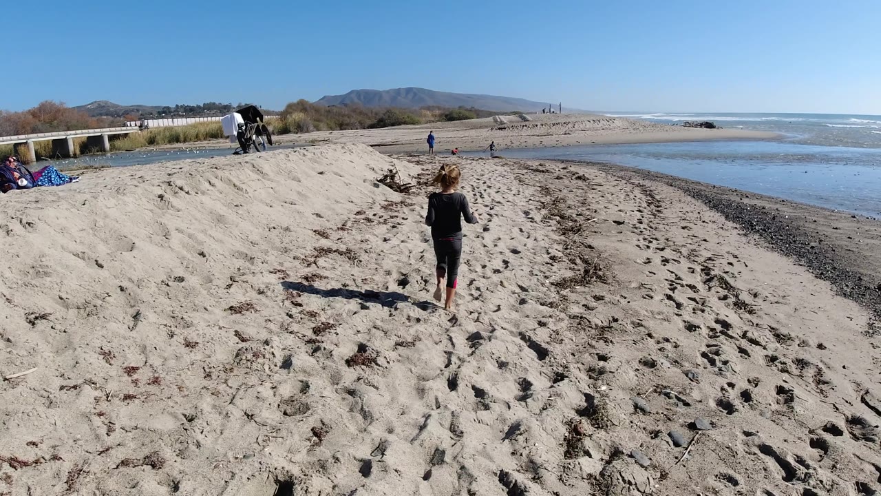 Child walking away on open beach with ocean at right