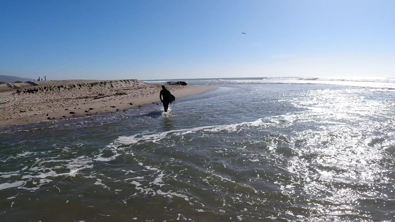 Man moving along the edge of shallow water and sand.