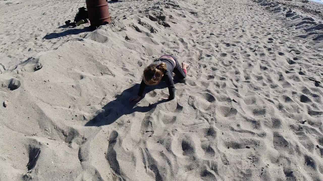 Child crawling across footprint-marked sand.