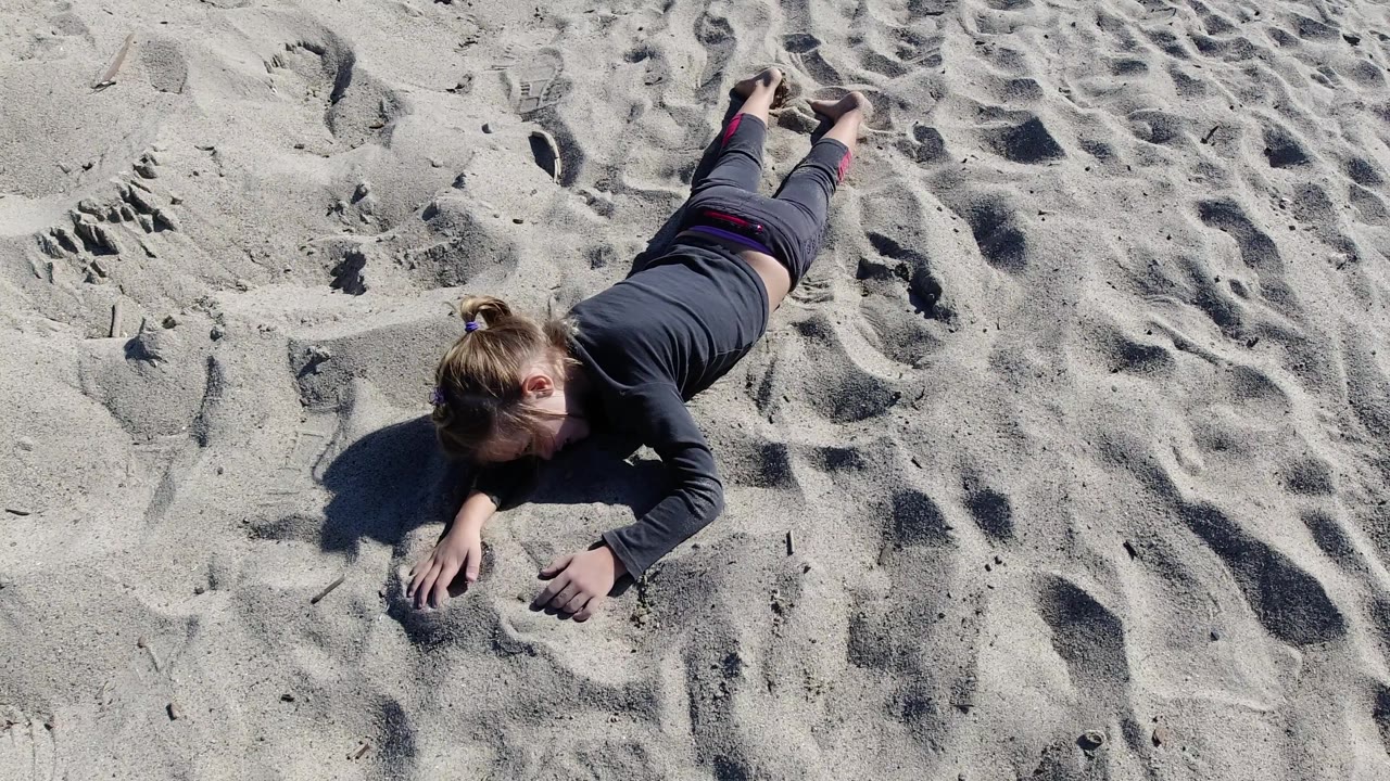 Overhead view of adult reaching across rippled sand.