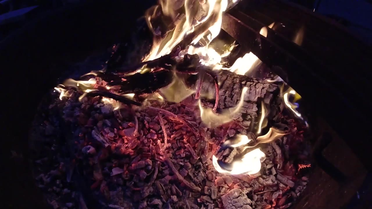 At two seconds, lighter ash-colored material is more distinct among the embers in the lower portion of the frame, while flame activity continues at the top and right; dark background, no people visible.