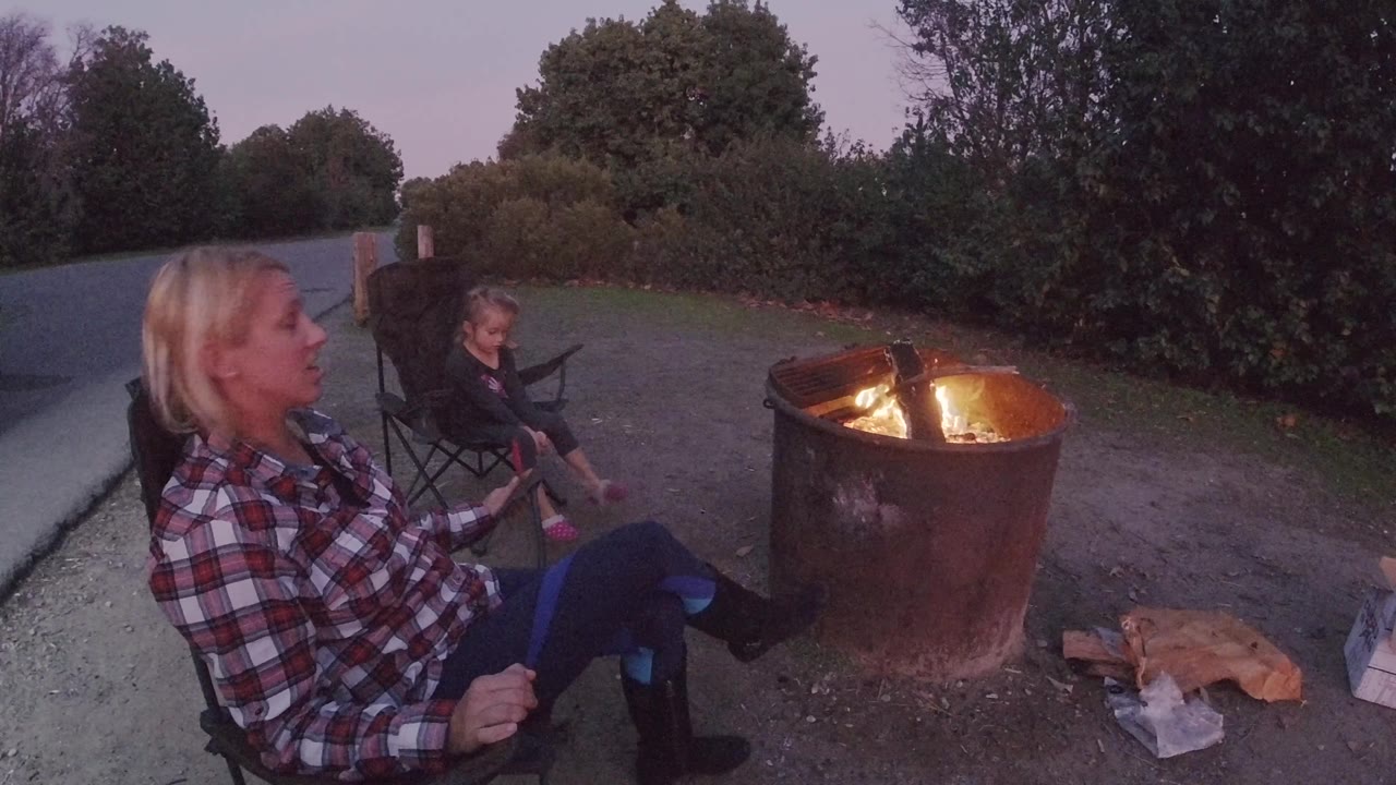 Side view of woman, child, and bonfire at dusk.