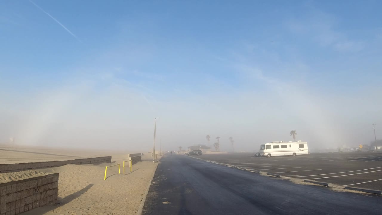 Empty road and parking lot under a blue sky with a faint light arc.