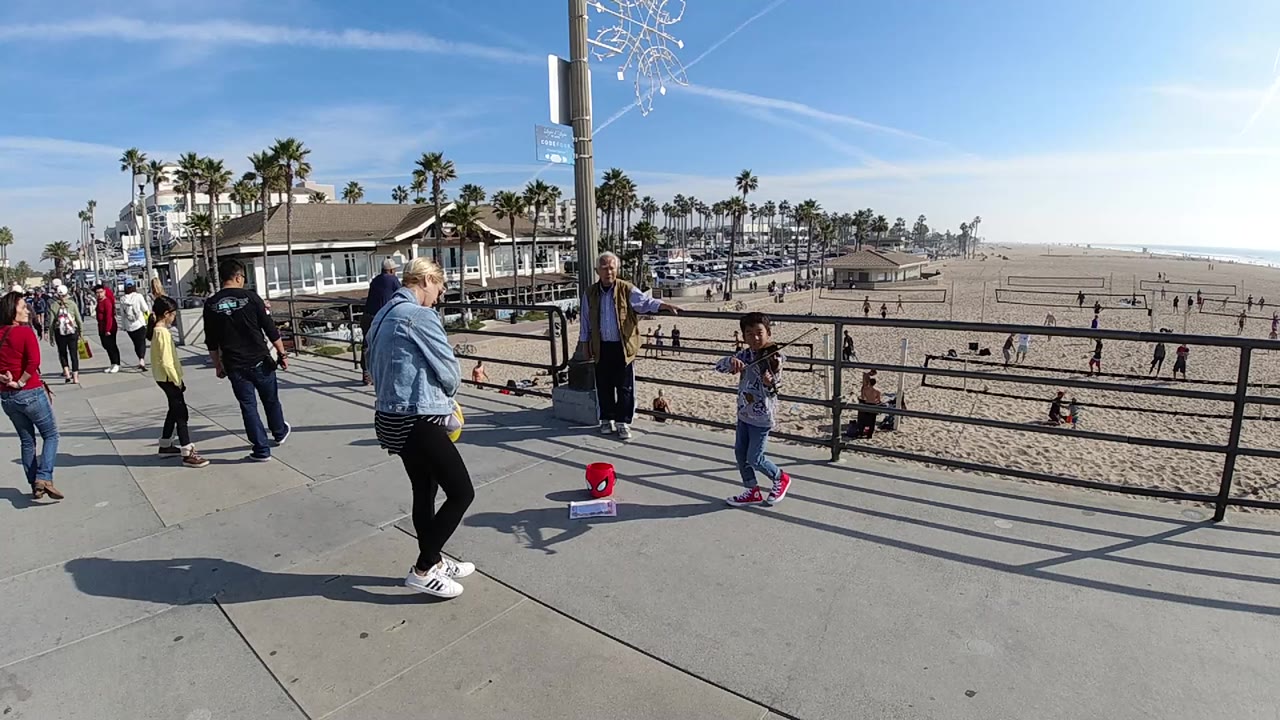 Child and woman continue dancing beside the beach railing.