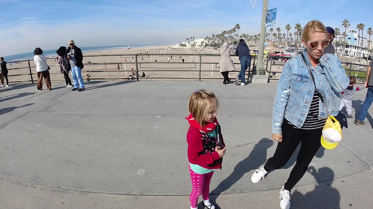 Woman and child remain near the boardwalk railing as pedestrians pass by.