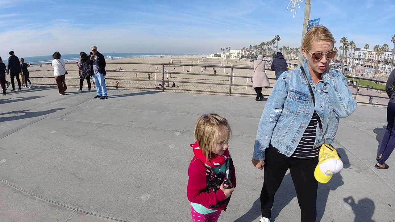 Foreground woman and child with pedestrians along a beach overlook.