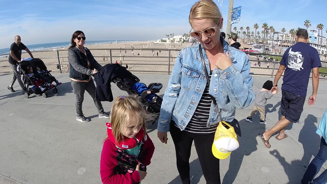 Mother and child near passing strollers above the beach.