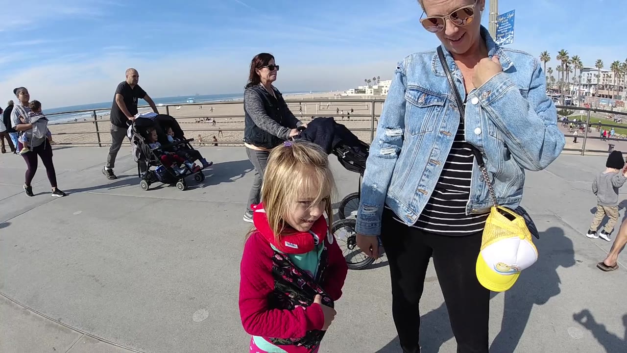 Adult and child near beach railing with stroller traffic in background