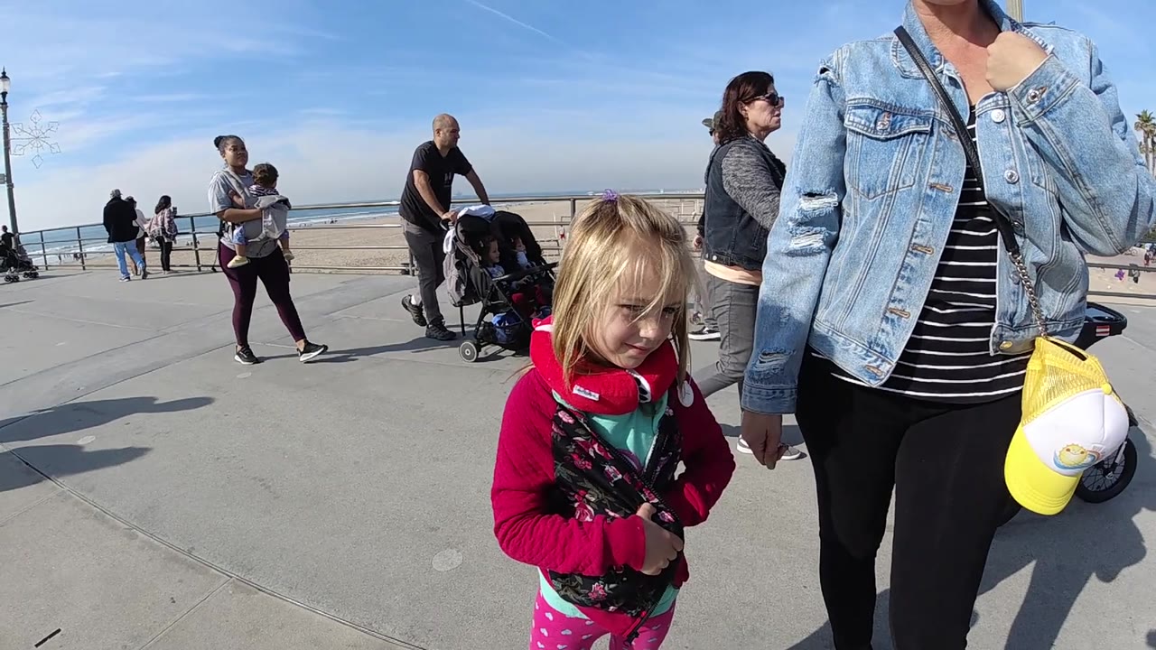 Adult and child in foreground on sunny beach promenade.