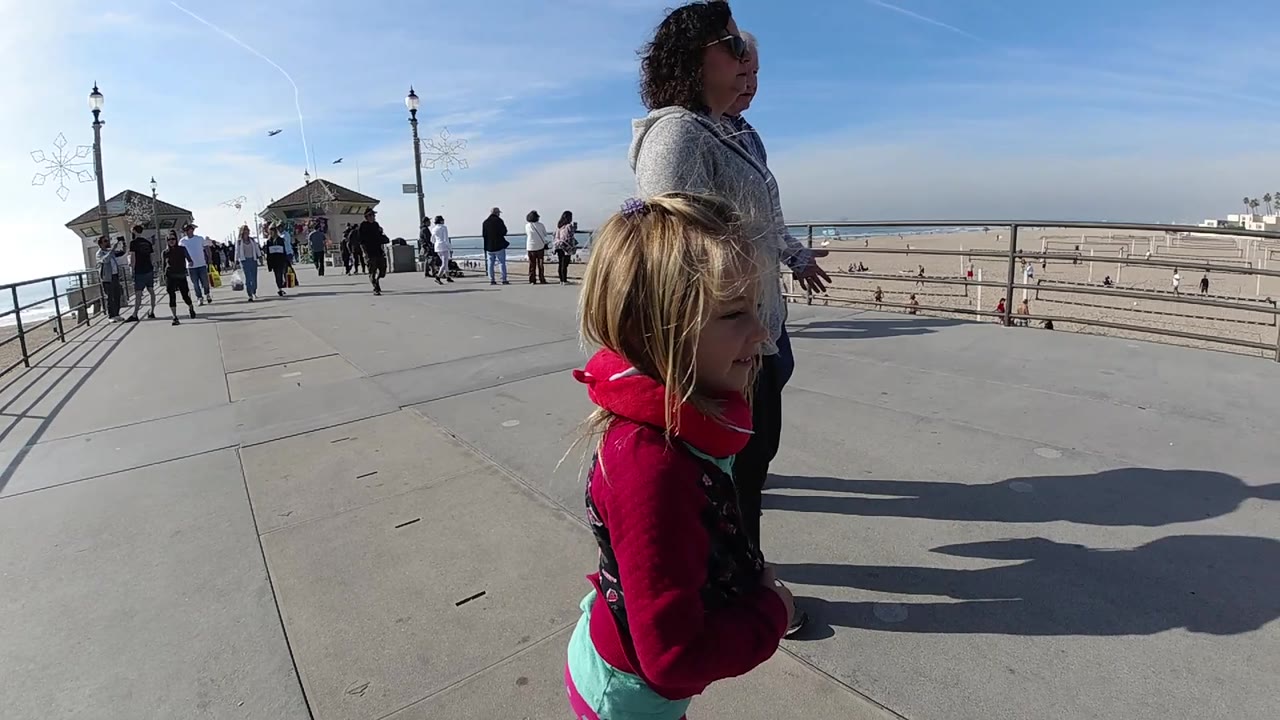 Girl glances beside a woman on a beachside boardwalk.