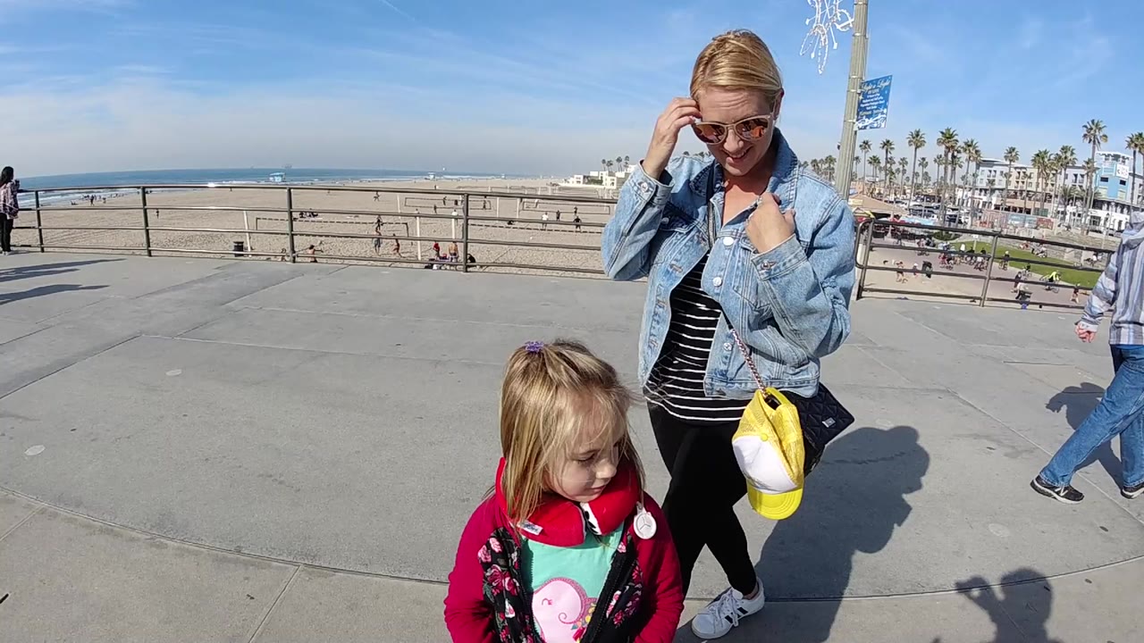 Woman and child continue walking near beach railings.