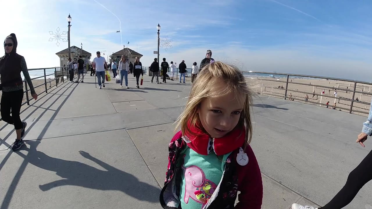 Child in red jacket on pier with a woman partly visible at the left edge.