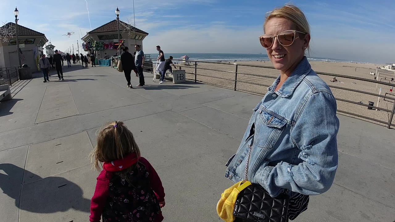 Woman and child near beach railings with pedestrians ahead.