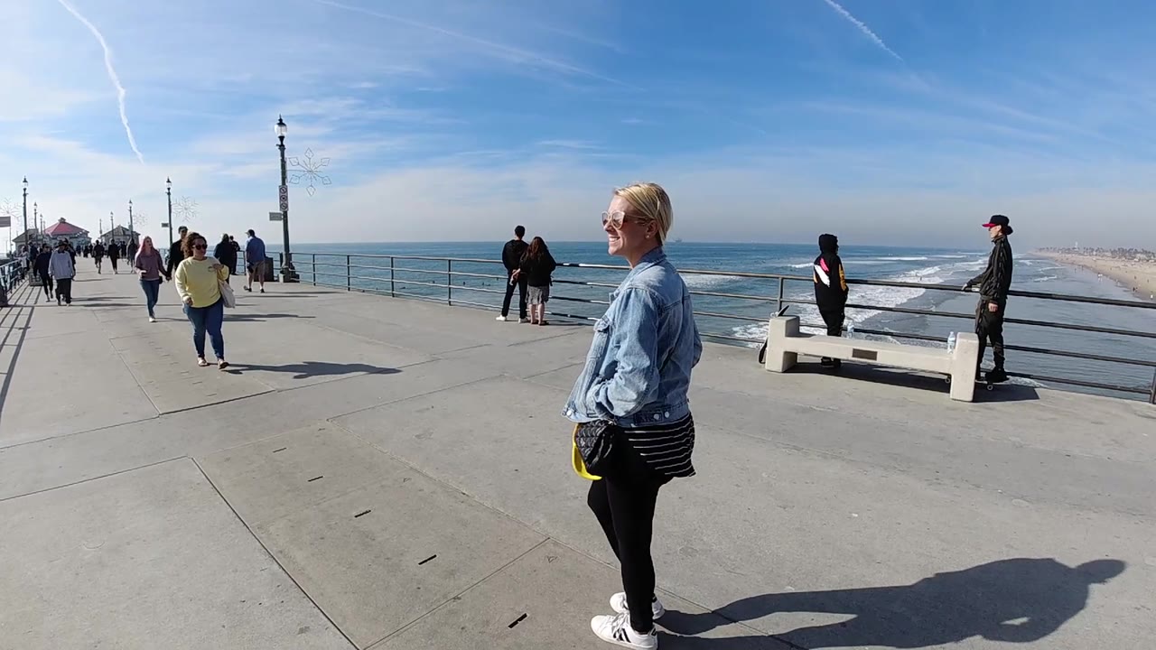 Woman walking past ocean railings on a bright pier