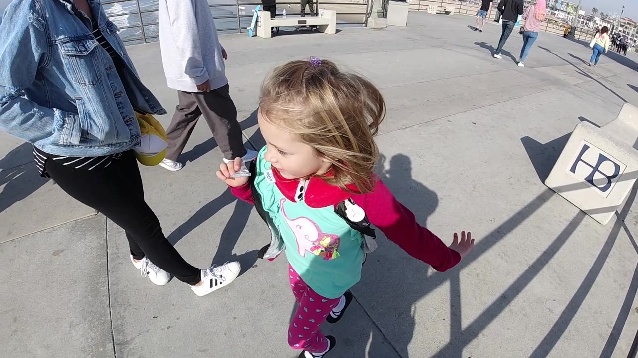 Close view of the girl running beside an adult on the boardwalk.