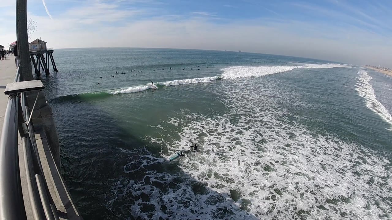 Pier posts and ocean waves with surfers beyond the break