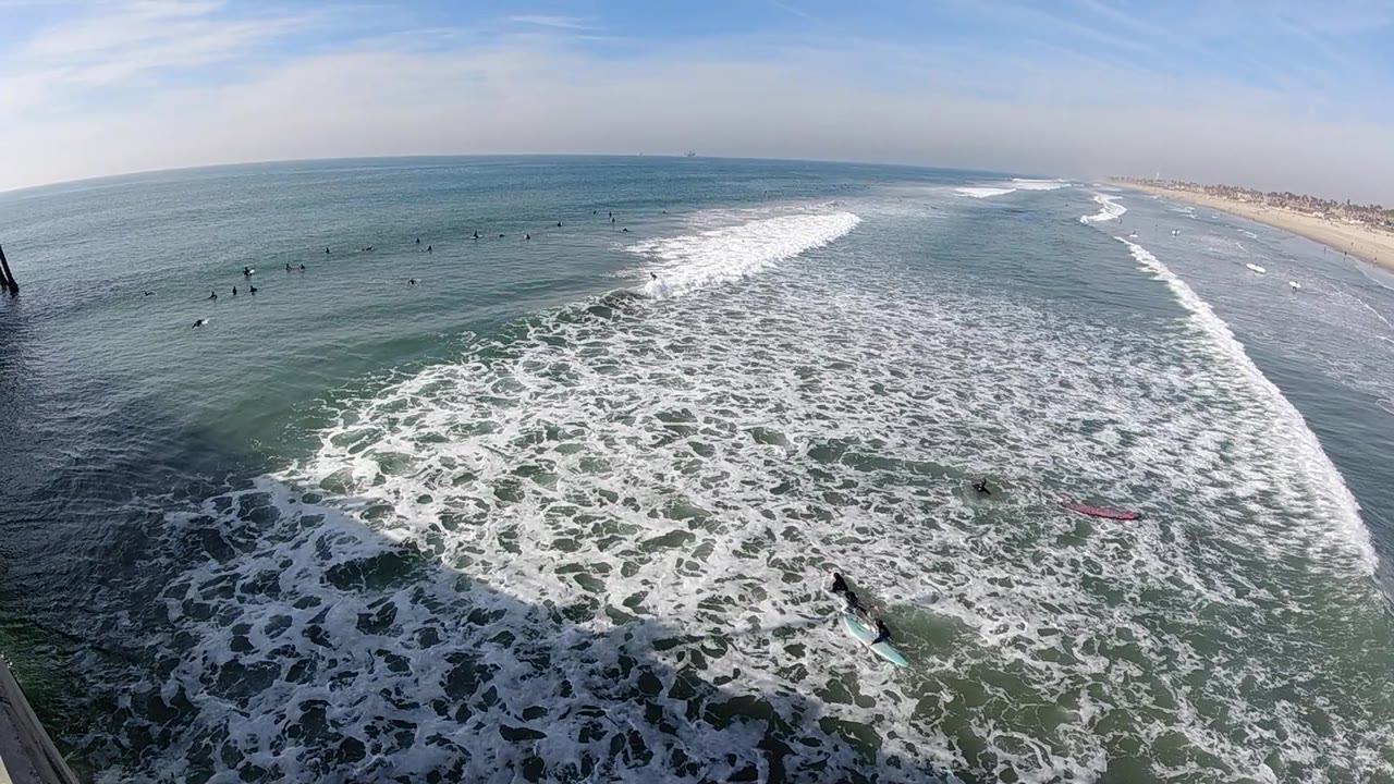 Surf breaks in clear water beside a distant sandy beach.
